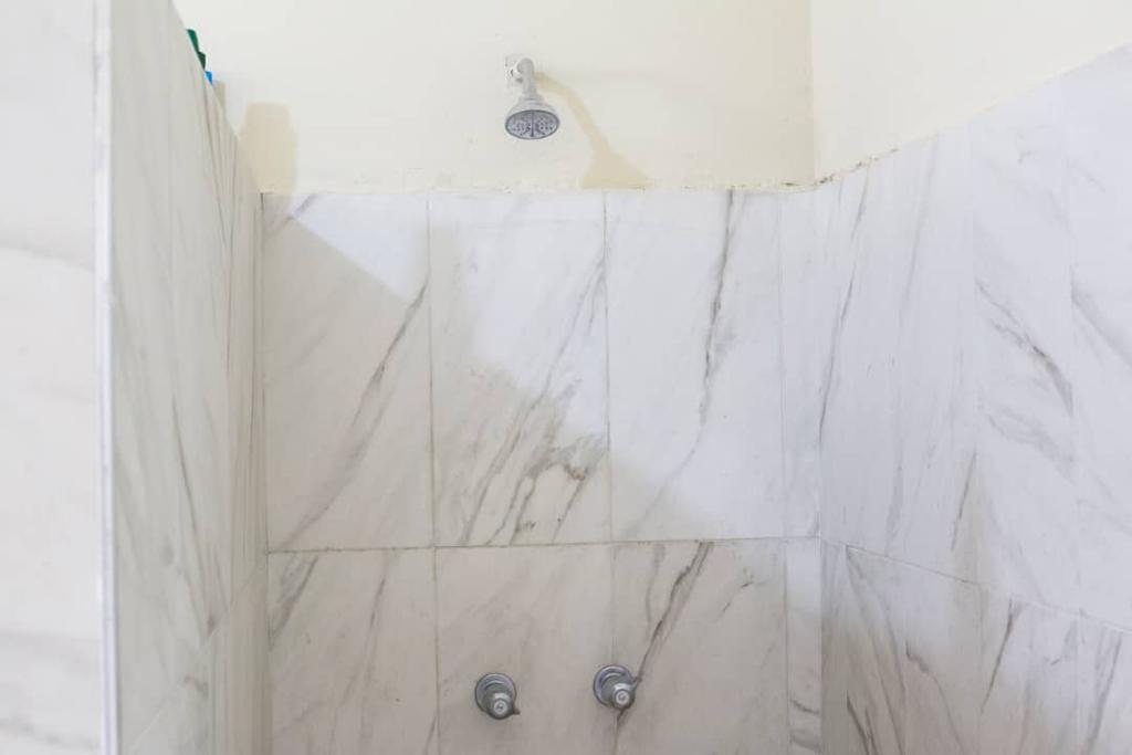 Shower with marble tile finish in UNAH dormitory bathroom